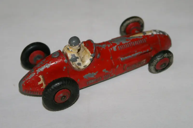 A playworn red Dinky Toys racing car with chipped paint (not a Thunderbirds model)