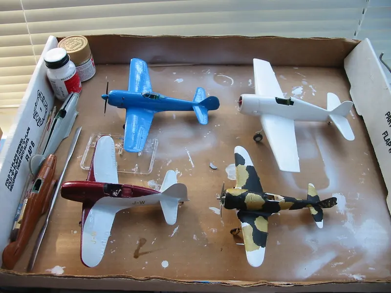 Part-painted model aircraft on a paint-spattered tray
