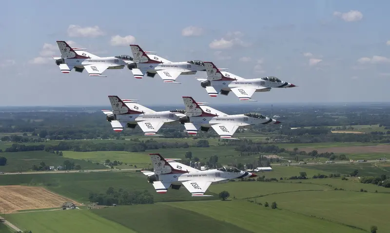 Six USAF Thunderbirds F-16s in tight formation over farmland